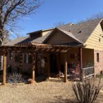 House With Wooden Pergola Landscaping Features And A Dry Lawn In A Suburban Setting Under A Clear Blue Sky