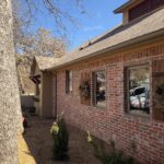 House Washing Of A Brick Exterior With Plants And A Clear Blue Sky In The Background