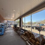 a clean and organized outdoor storage area with stacked pallets containing various supplies and products visible through large windows