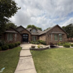 well maintained brick home with landscaped front yard and clear walkway under partly cloudy sky